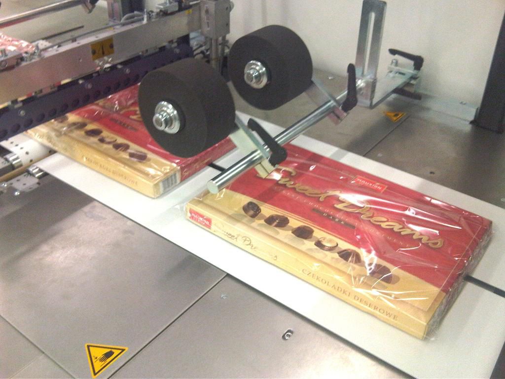 Cajas de bombones que se encuentran pasando el proceso de máquina retractiladora para plastificar el producto